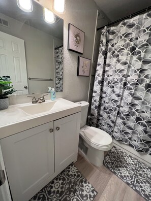 A bathroom with a white sink, mirror, toilet, and shower curtain with a black and white pattern. - Downtown Dallas LUXE Urban Haven 1BD Retreat (Dallas)