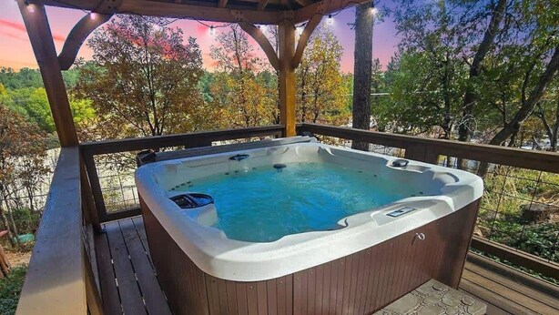 A hot tub under a wooden pergola with a view of trees and a sunset. - Relax. Soak. Explore. Repeat. | Bella Luna Cabin (Ruidoso)