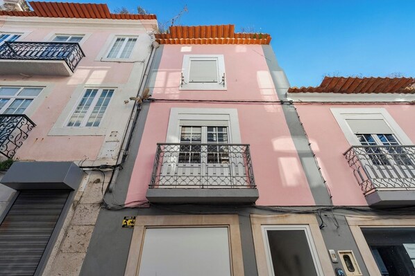 Un bâtiment rose doté de balcons et d’une porte de garage.
