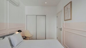 Ein Schlafzimmer mit Bett, Nachttisch, Lampe, Stuhl und Kleiderschrank.