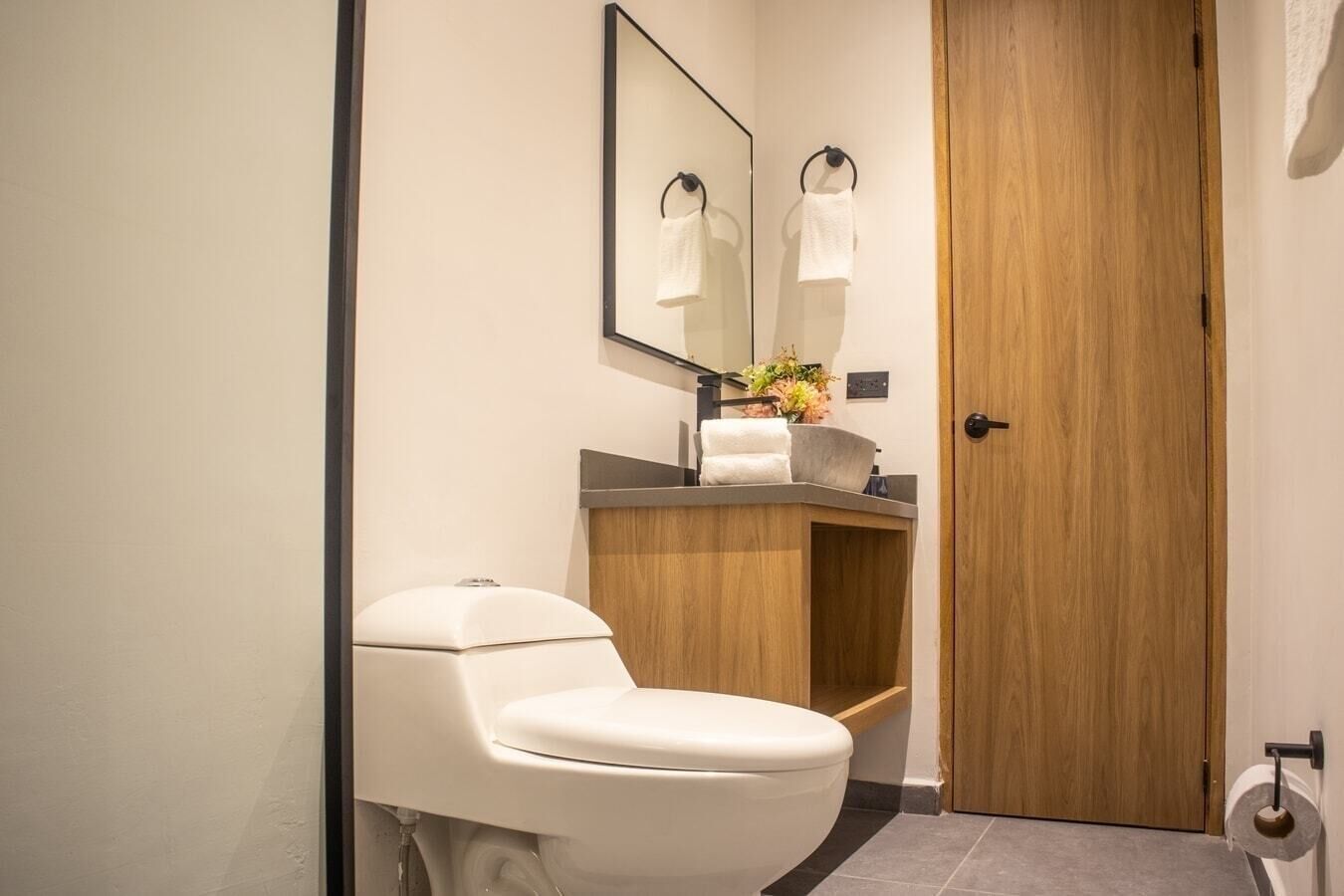 Un baño moderno con inodoro, lavamanos y espejo.