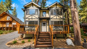 A two-story lodge with a central entrance, wooden railings, and a stone pathway leading to the door. - Mama Bear's Cottage - Portable AC, Close to Slopes, Fenced Yard, Pet Friendly (Big Bear Lake)