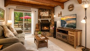 A cozy living room with a fireplace, a sofa, a coffee table, and a television. - Mama Bear's Cottage - Portable AC, Close to Slopes, Fenced Yard, Pet Friendly (Big Bear Lake)