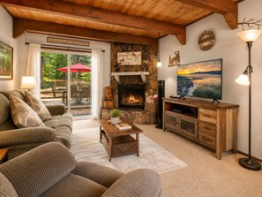 A cozy living room with a fireplace, a sofa, a coffee table, and a television. - Mama Bear's Cottage - Portable AC, Close to Slopes, Fenced Yard, Pet Friendly (Big Bear Lake)