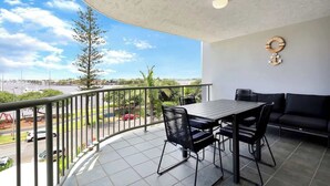 En balkon med et bord, stole, en sofa og udsigt over byen.