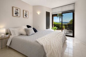 Una camera da letto con un letto grande, un comodino, una lampada a parete e vista all'esterno tramite una porta scorrevole.