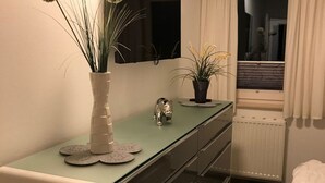 Ein Schlafzimmer mit einem grünen Schminktisch, einem Spiegel, einer Heizung und zwei Blumentöpfen.