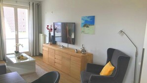Ein modernes Wohnzimmer mit einem Holzschrank, einem Flachbildfernseher, einem Gemälde und einer Lampe.
