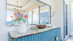 A modern kitchen with a marble countertop, a blue cabinet, and a large window offering a view of the sea. - Amazing two bedroom beach front condo W1105 (Puerto Peñasco)