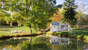 Ein Haus mit Teich, umgeben von Bäumen und Gras.
