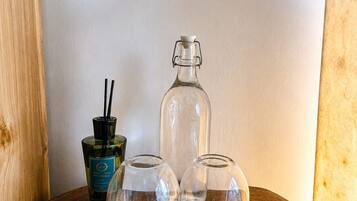 Una mesa de madera con tres vasos de vidrio transparente y una botella con tapón negro.