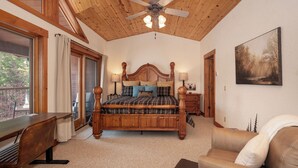 A bedroom with a wooden ceiling, a large bed with multiple pillows, a desk, a chair, and a couch. - Luxury Lakefront Retreat on Lake Granby Near Snowmobiling (Grand Lake)