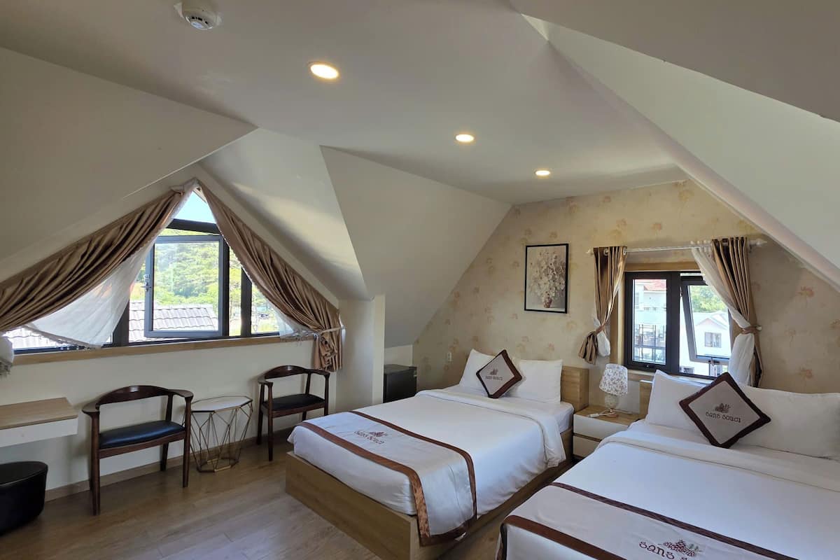 A bedroom with two beds, a desk, and a chair.