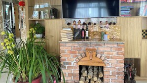 A living room with a brick fireplace, a flat-screen TV, and a bookshelf filled with books and decorative items. - Vô Tư Hotel (Xuan Huong - Da Lat)