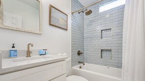 A bathroom with a white vanity, a toilet, a bathtub, and a shower area with a glass door.