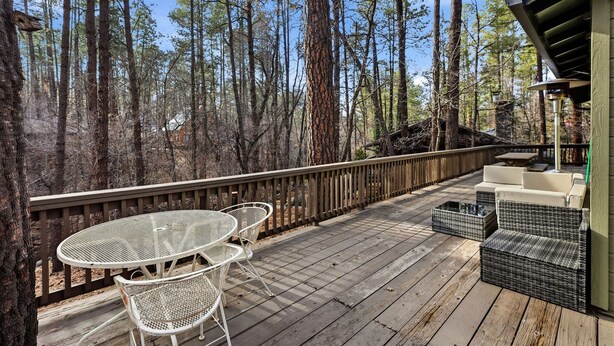 A wooden deck with outdoor furniture, surrounded by tall trees. - Peaceful Prescott Cabin Near Goldwater Lake (Prescott)