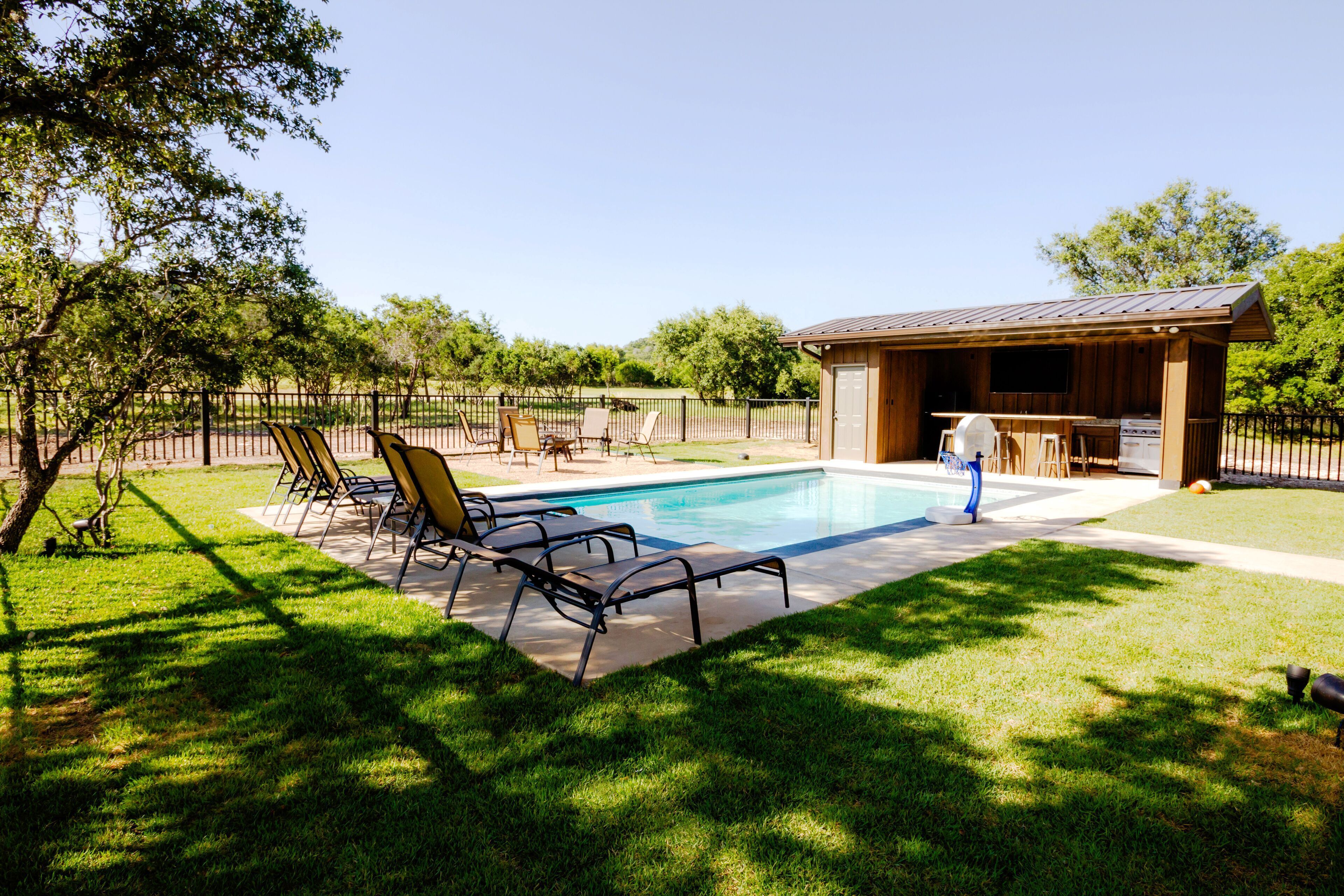 A backyard with a swimming pool, outdoor seating, and a barbecue area.