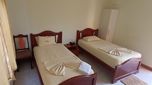 A room with two single beds, a wooden wardrobe, a nightstand with a phone, and a curtain. - HOTEL SHEKINAH INTERNACIONAL (Esmeraldas)