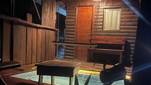 Eine Holzhütte mit kleinem Pool, einem Tisch und einem Stuhl.