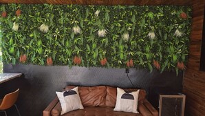 Et værelse med en brun lædersofa, to puder, trælofter og en grøn væg med planter.