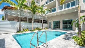 A modern hotel with a swimming pool, palm trees, and a covered outdoor area. - Charming 2-bedroom apartment with AC, fitness room in Hollywood (Hollywood)