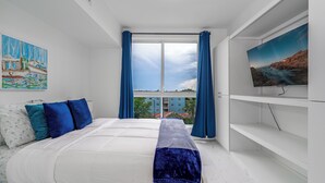 A bedroom with a bed, a TV, a painting, and a view of the city. - Charming 2-bedroom apartment with AC, fitness room in Hollywood (Hollywood)