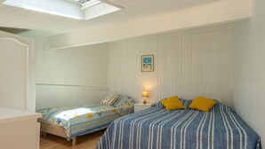 A bedroom with two beds, a skylight, wooden flooring, and a framed picture on the wall. - Apartment Nauzan by Interhome (Saint Palais sur mer)
