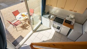 A modern kitchen with a built-in oven, microwave, and sink. There is a dining area with a table and chairs outside. - Apartment Nauzan by Interhome (Saint Palais sur mer)