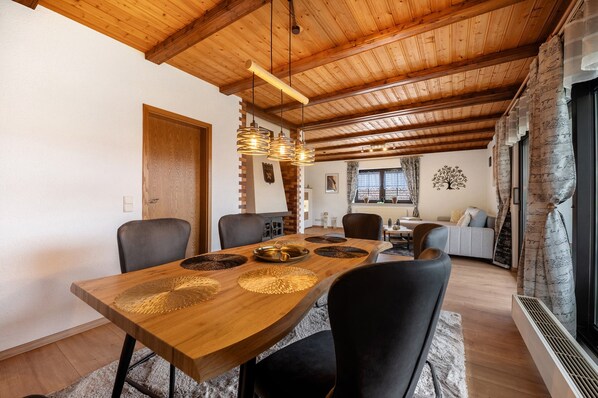 A wooden dining table with chairs, a chandelier, and a fireplace.