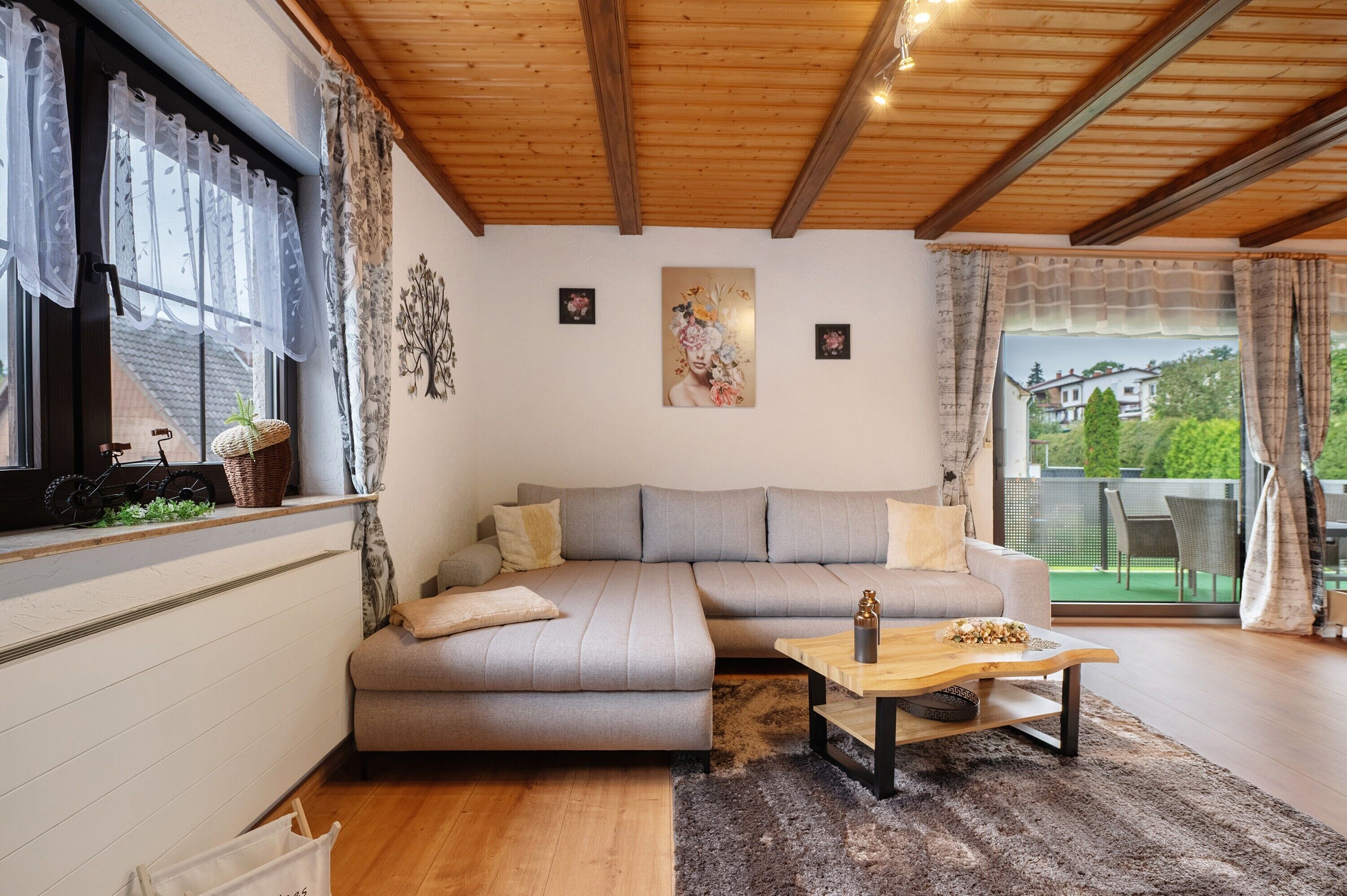 A modern living room with a grey sectional sofa, a wooden coffee table, and a view of a balcony.