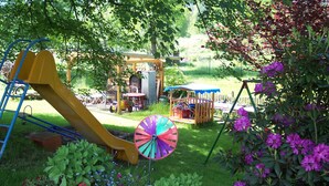 Een speeltuin met een glijbaan, een schommel en een kleurrijk windvaantje.