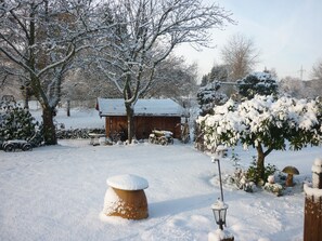 A snow-covered outdoor area with a wooden structure, a bench, and a lamp post.