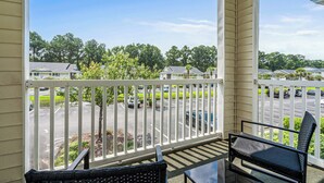 A balcony with a view of a parking lot and houses.