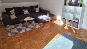 Un salon moderne avec un canapé, une petite table, un tapis, un meuble et un tableau.