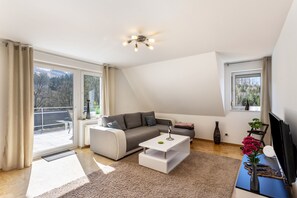 A modern living room with a sofa, coffee table, and TV. - Apartment 'Raus Aufs Land' with Balcony and Wi-Fi (Schmallenberg)