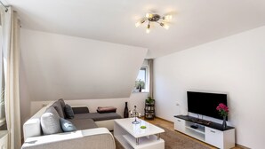 En moderne stue med sofa, sofabord, TV-møbel og en loftlampe.