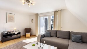 En moderne stue med en grå sofa, et hvidt sofabord, en sort kandelaber og et indrammet billede på væggen.