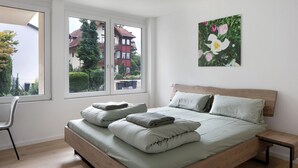 Une chambre à coucher avec un lit, une chaise, une fenêtre et un tableau accroché au mur.