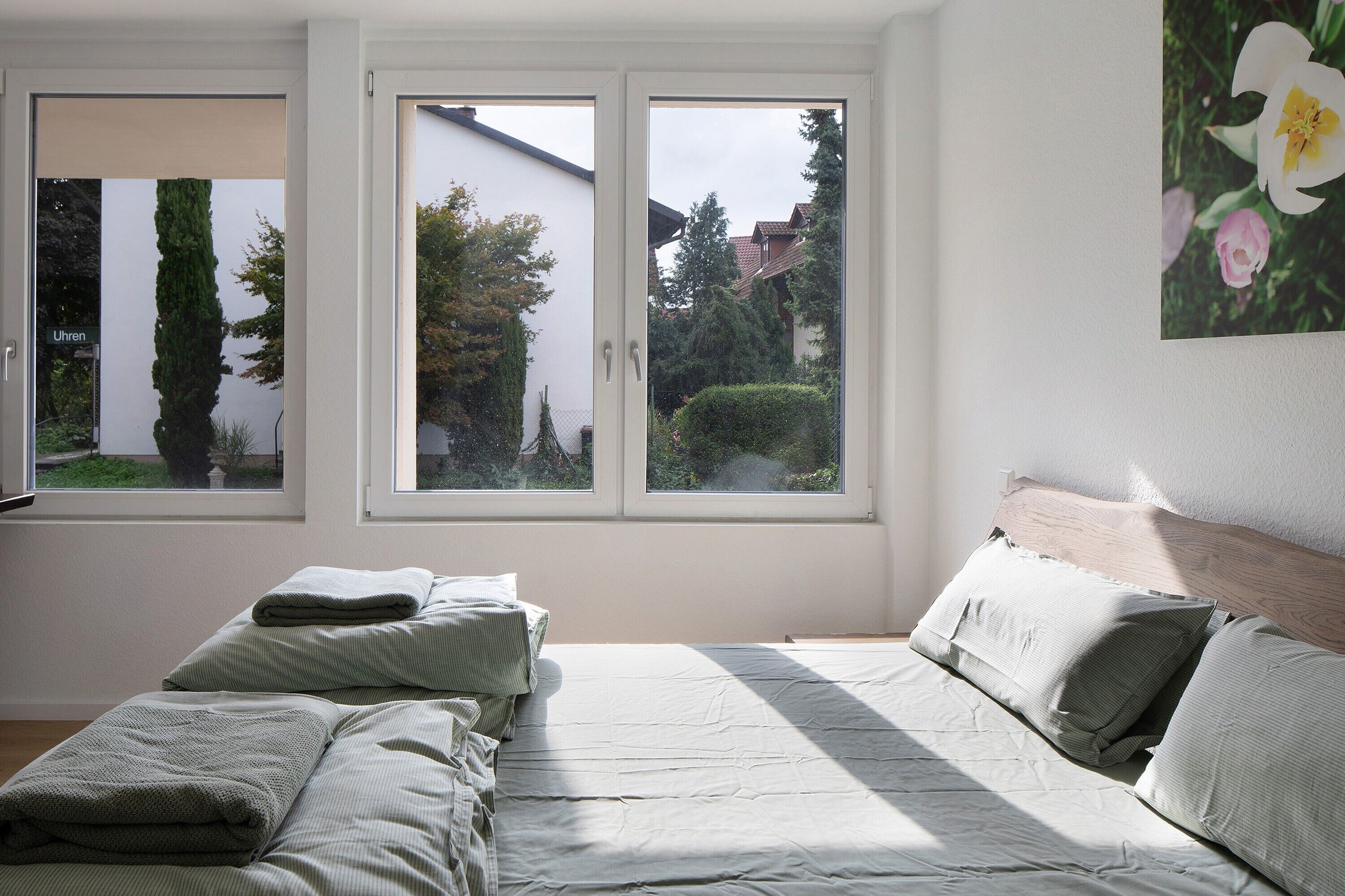 Un dormitorio con cama, almohadas y vistas a través de una ventana.