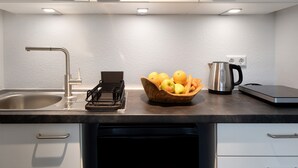 Une cuisine moderne équipée d’un évier en acier inoxydable, d’une bouilloire, d’un panier à fruits et d’une machine à café.
