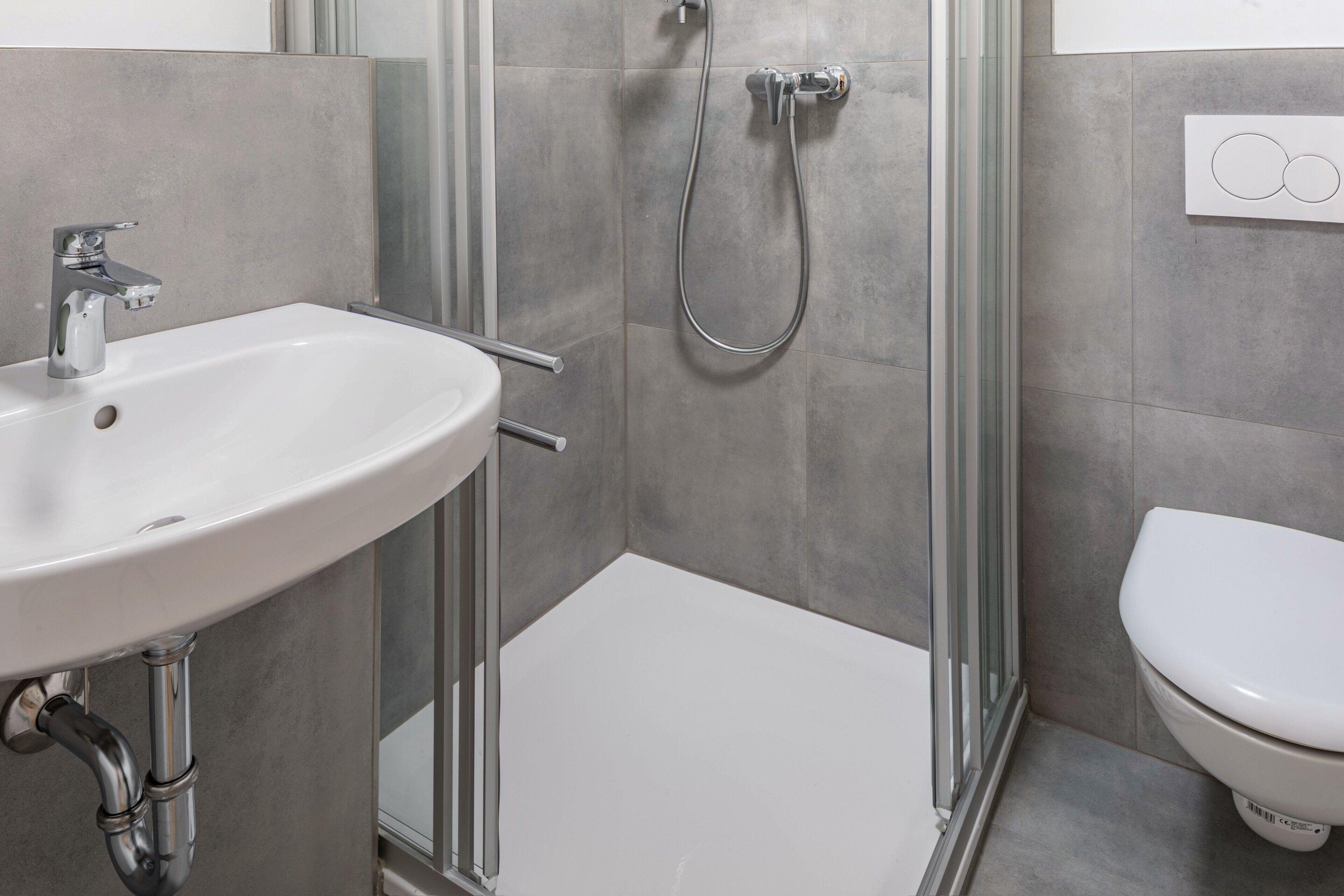 A bathroom with a white sink, a shower, and a toilet.