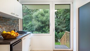 Una cocina moderna con un ventanal grande, una terraza de madera y lavavajillas integrado.