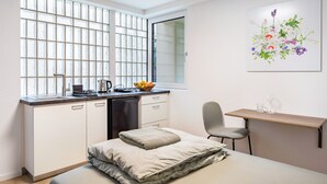 A compact room with a kitchenette, a bed, a desk, and a window with a view. - Studio Apartment 'Schlatt' with Wi-Fi (Bad Krozingen)