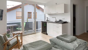 Un apartamento moderno con cocina, comedor y balcón con vista a un edificio.
