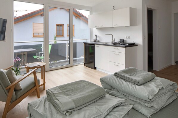 Eine moderne Wohnung mit Küche, Essbereich und einem Balkon mit Blick auf ein Gebäude.