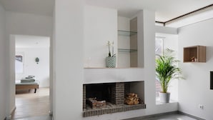 Un interior moderno con chimenea, una planta en maceta y una cama al fondo.