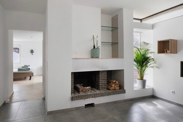 A modern interior with a fireplace, a potted plant, and a bed in the background.