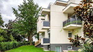 A multi-story residential building with balconies, a green lawn, and mature trees. - Studio Apartment 'Belchen' with balcony and Wi-Fi (Bad Krozingen)