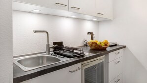 Une cuisine moderne dotée d’un évier en acier inoxydable, d’un égouttoir et d’un panier à fruits posés sur le plan de travail.