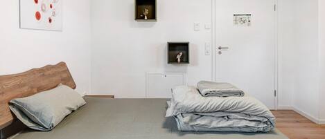 Un dormitorio con una cama, cabecera de madera, un cuadro en la pared y una puerta con un cartel.